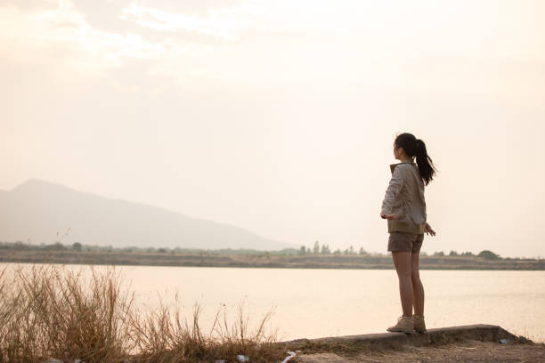 istock a woman waiting for the sunset behind the mountain 1402109603