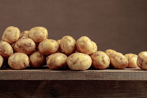 Fresh organic potatoes on a old wooden table. Copy space.