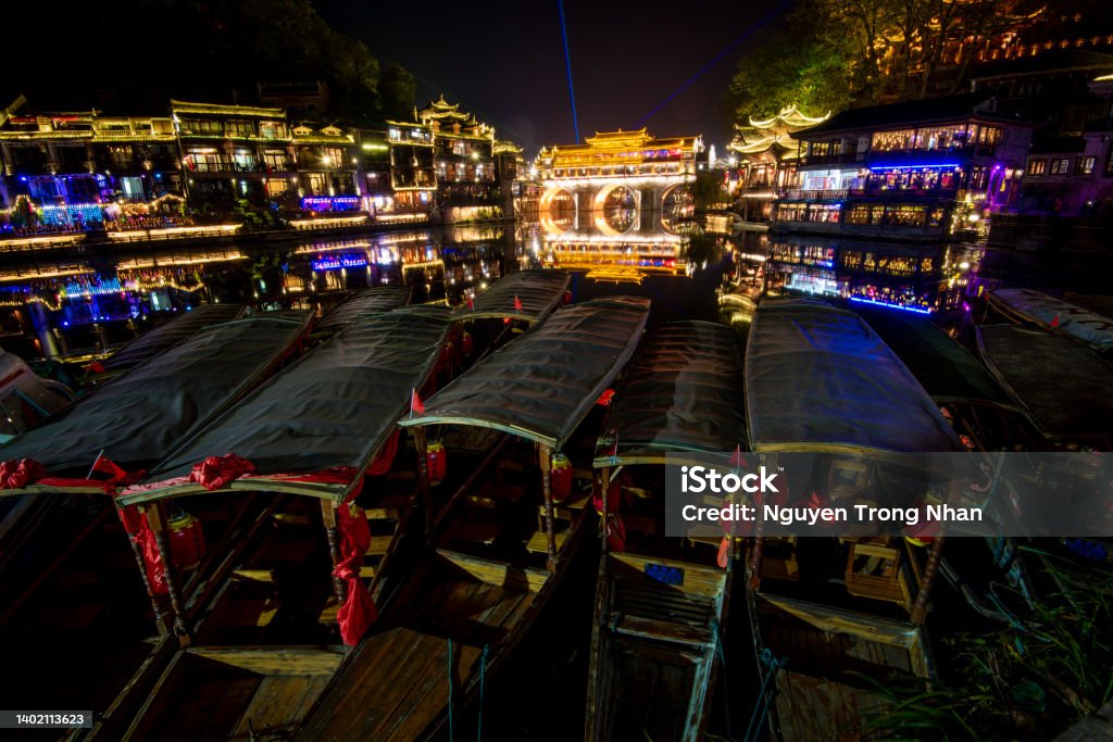 View of illuminated at night riverside houses in ancient town of Fenghuang known as Phoenix, China Ancient Stock Photo