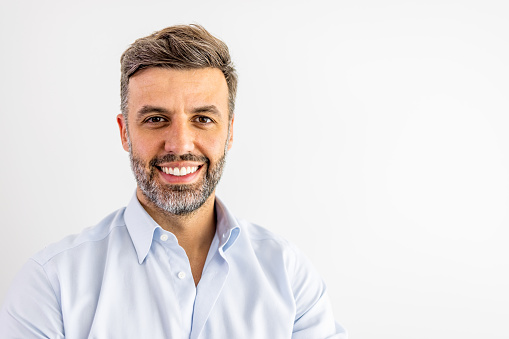 Successful businessman cheerfully smiling and looking at camera while standing against white background