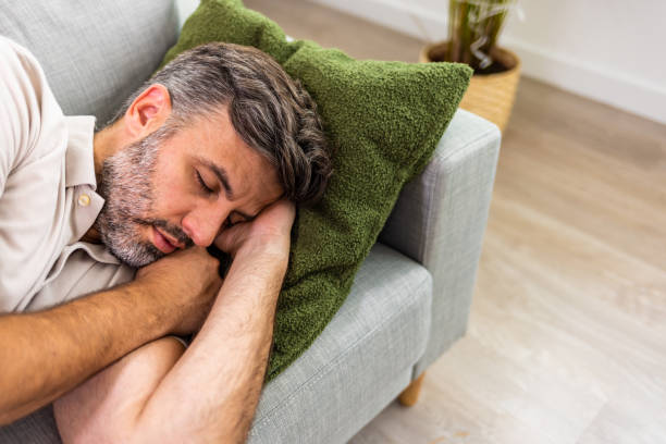 photo d’un homme se relaxant sur le canapé à la maison - lying down men isolated young adult photos et images de collection