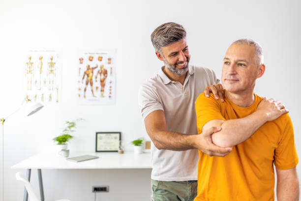 Man having chiropractic back adjustment Physical therapists are checking patients elbows at the clinic office room physical therapy stretching stock pictures, royalty-free photos & images