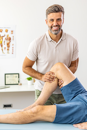 Male doctor examining a knee of a senior gentleman during an appointment.