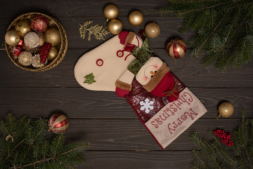 Rustic wooden background decorated with tree branches, gift sock and box of Christmas ornaments