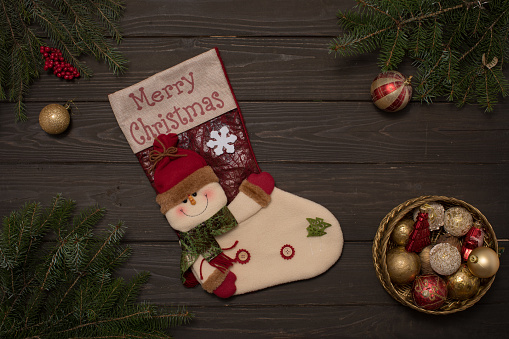 Rustic wooden background decorated with tree branches, gift sock and box with Christmas ornaments