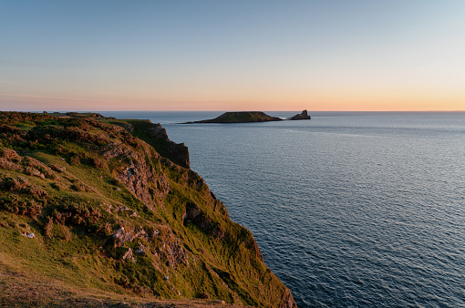 The spectacular landscape of Worms Head at Rhossili Bay on the Gower Peninsula, South Wales, UK. The name Worm's Head is derived from an Old English word 'wyrm' for 'sea serpent'