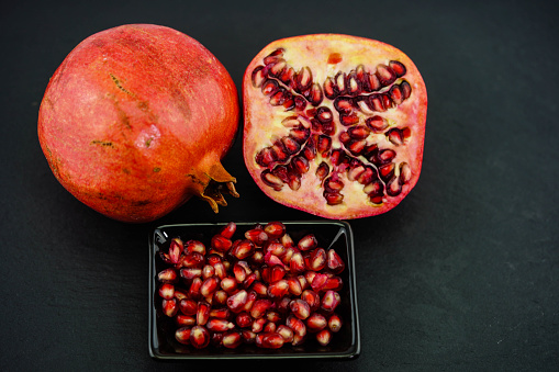 Freshly sliced red pomegranate on a black slate