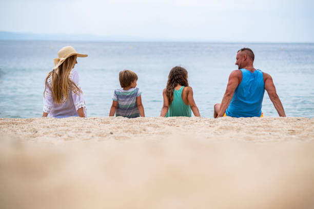 istock Family sitting on sand rear view 1402120429