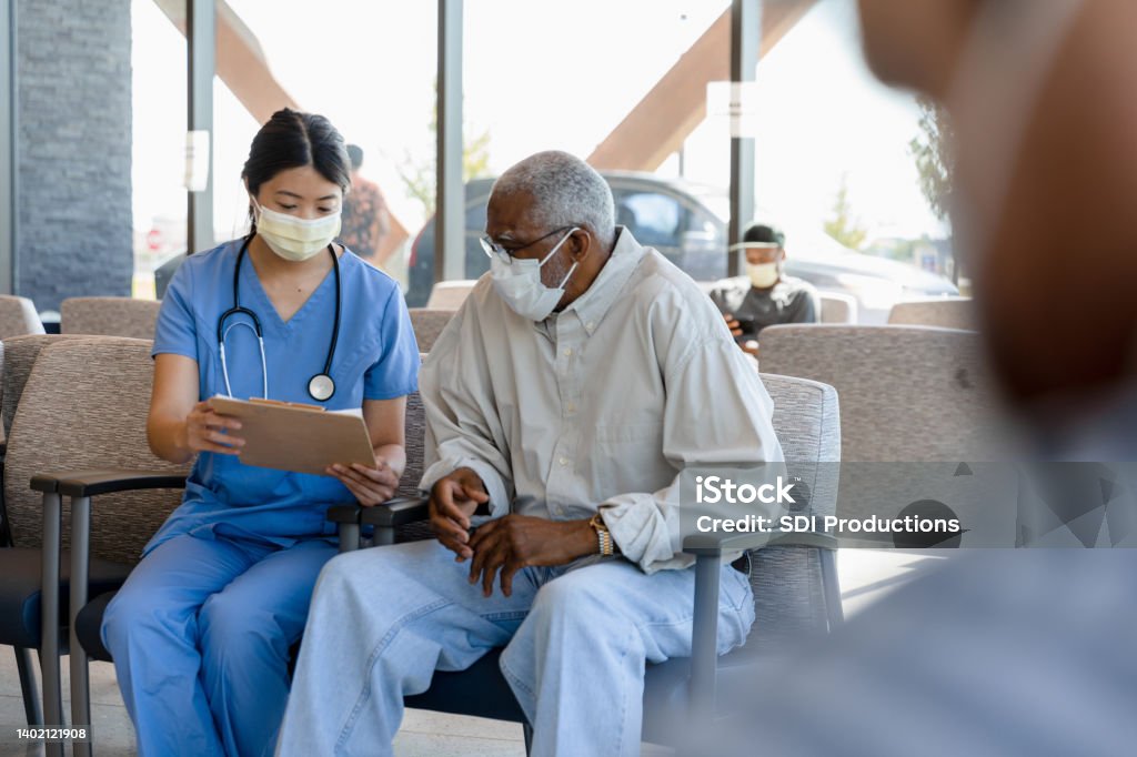 Nurse helps elderly patient The nurse helps the senior adult patient to fill out his paperwork to see the doctor. Patient Stock Photo