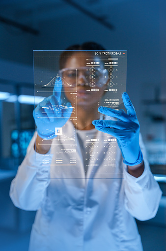 Young beautiful African-American medic in a lab coat and protective gloves works with a HUD screen in a futuristic lab in a late evening, we see her from the waist up