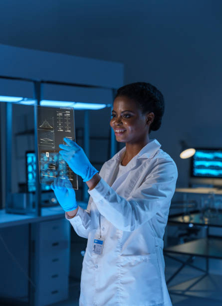 istock A young smiling female scientist in a lab coat works with a small HUD screen in a modern laboratory 1402123038