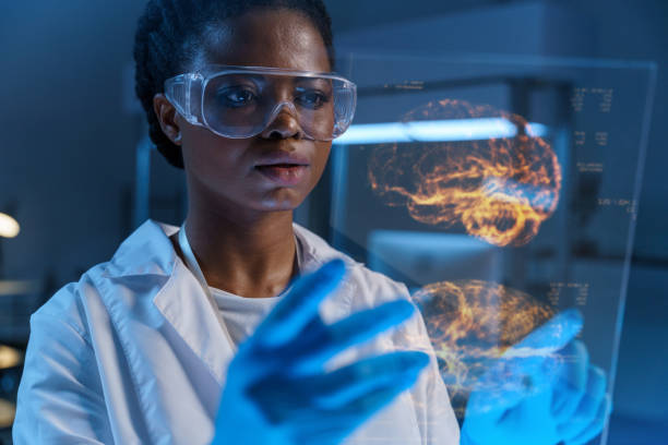 ein junger ernsthafter afroamerikanischer arzt im laborkittel arbeitet mit einem kleinen hud-bildschirm mit einem bild eines gehirns in einem modernen labor - lab coat women one person female stock-fotos und bilder