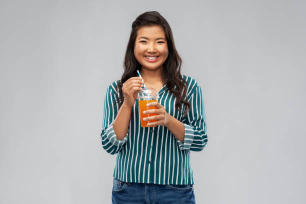 mujer asiática con jugo en vaso de plástico con pajita - drinking straw drinking juice women fotografías e imágenes de stock