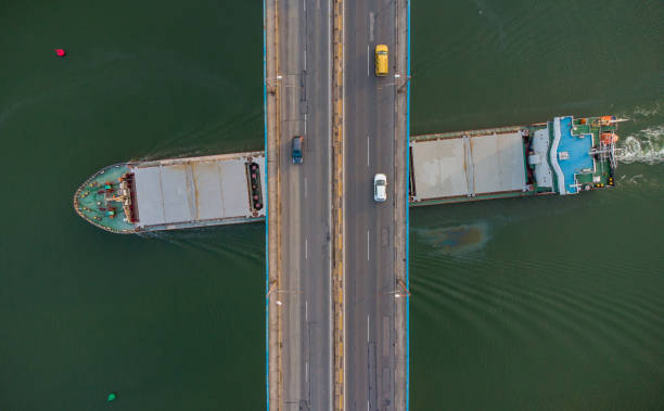 istock Large general cargo ship tanker bulk carrier passing under a bridge with heavy traffic, aerial view. 1402123178