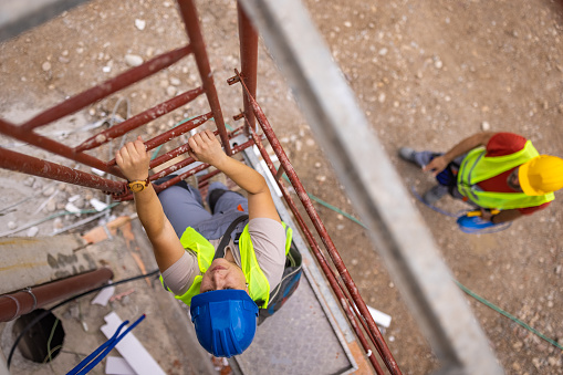 High angle view of male construction worker climbing on a scaffolding