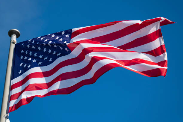 istock American flag waving in the wind against blue sky. 1402129119