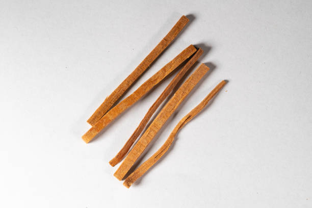 Close-up of Cinnamon sticks in a glass bowl isolated against plain white background. Cinnamon plays a major role in Indian spices, recipes and ayurvedic herbal remedies.