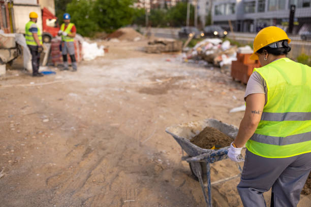 At the construction site, Caucasian female construction worker, pushing the cart with sand