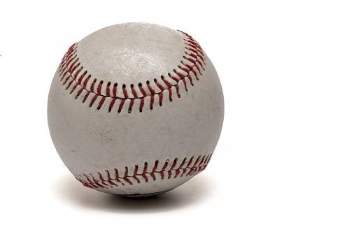 Close up of used white baseball with red stitching on white background