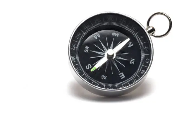Close up of metal retro magnetic compass with compass needle pointing north south direction on white background as concept for direction and navigation