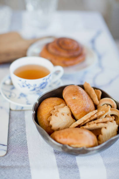 Tea time. Cup with tea and pastry loafs, cookies in bowl on the table