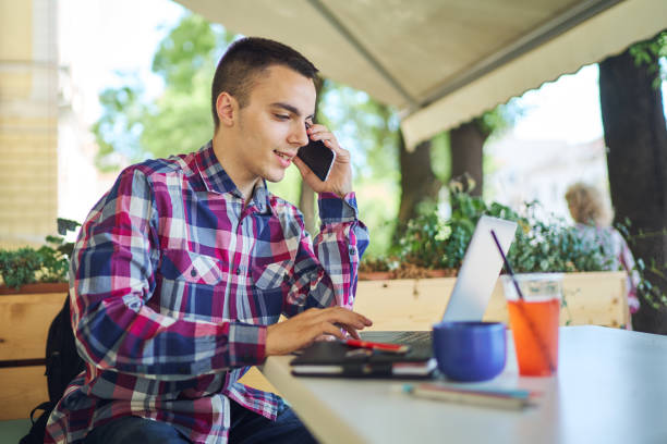 Young freelancer working with phone at coffee shop