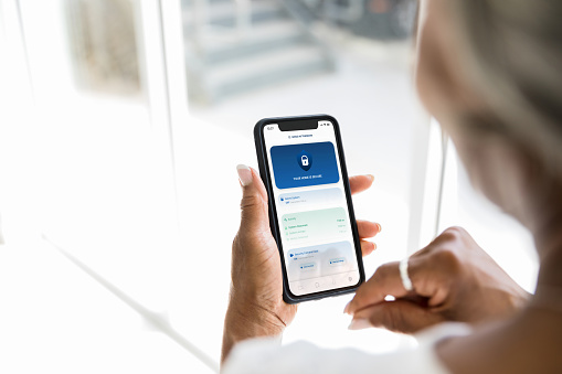 An unrecognizable woman checks to see if the door to her home is locked by using a mobile app.