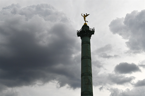 Paris, France-06 04 2022: Silhouette of the July Column just before a rain storm.The July column (Colonne de Juillet) which commemorates the events of the July Revolution (1830) stands at the center of the Bastille square in Paris, France.