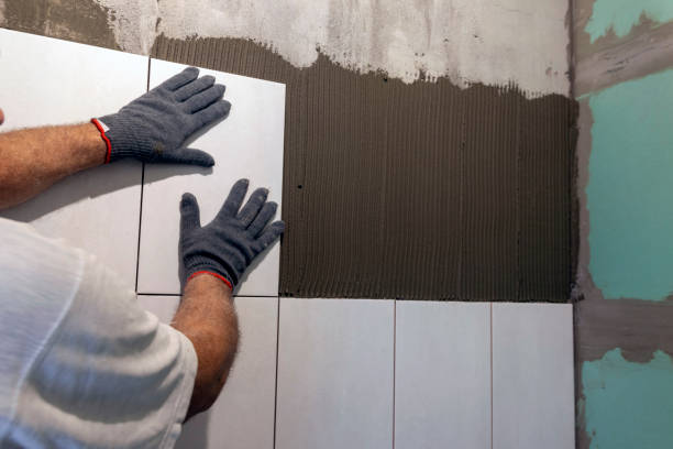 istock A worker lays ceramic tiles on a wall. Laying tiles using glue. 1402141428