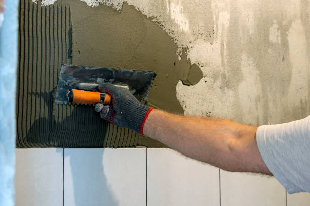 istock A worker lays ceramic tiles on a wall. Laying tiles using glue. 1402143469