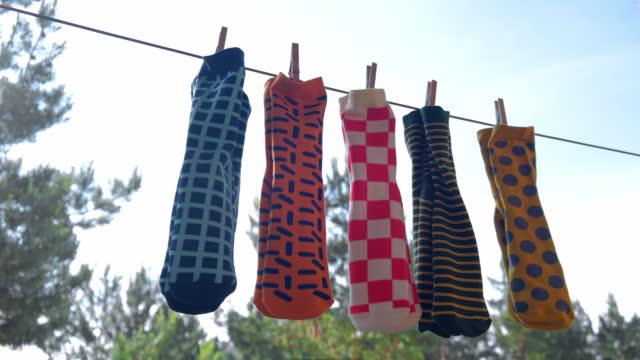 colored men's socks with bright different patterns are dried on a rope with clothespins. close-up.