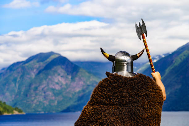 Viking warrior with helmet and axe on fjord shore in Norway. Tourism and traveling concept
