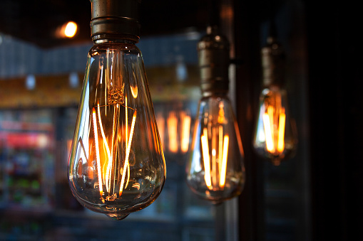 Edison light bulb lamps hanging near cafe window close-up