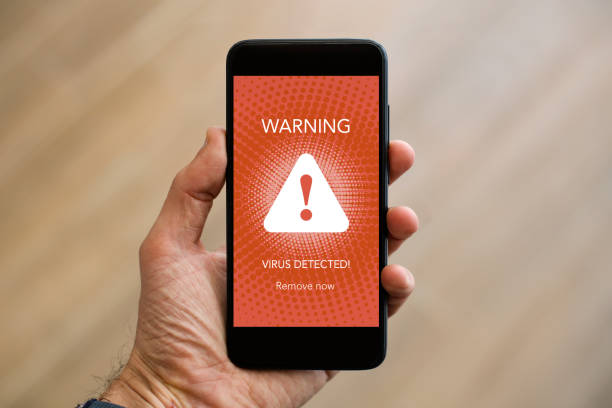 Virus detected on smart phone Unrecognizable Caucasian man holding a modern smart phone with an antivirus alert on touch screen. phone spam photos stock pictures, royalty-free photos & images