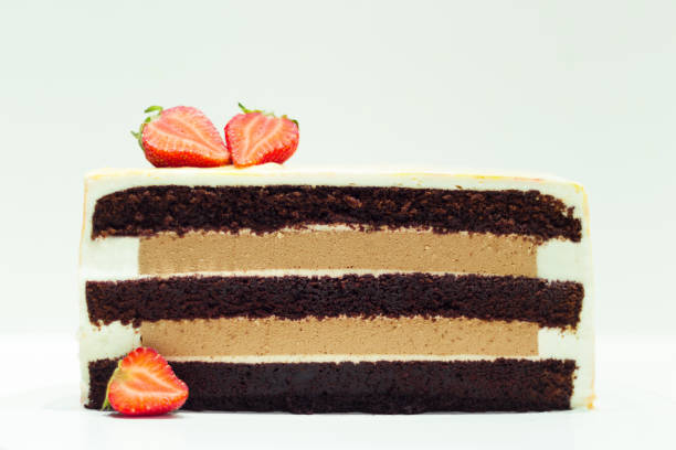 istock Cake cut with chocolate sponge bisquit layers with coffee mousse and cream cheese decorated with strawberries on the white background 1402149582