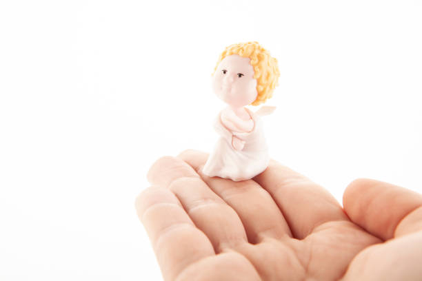 image of miniature angel figure hand white background