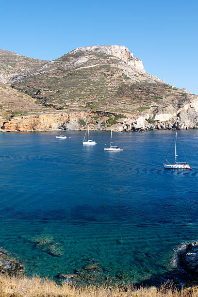 Four boat stay calm in a beautiful bay in Folegandros, Cyclades Islands, Greece. Turuoise water all around.