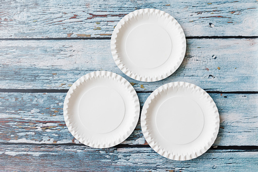 Flat lay composition with eco-friendly paper plate on light blue wooden background. Kraft paper plates, Recyclable paperware, zero waste concept. Selective focus