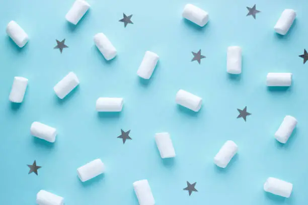 Geometric pattern of white marshmallows and stars on blue pastel background. Food concept in minimal flatlay style. Horizontal image top view.