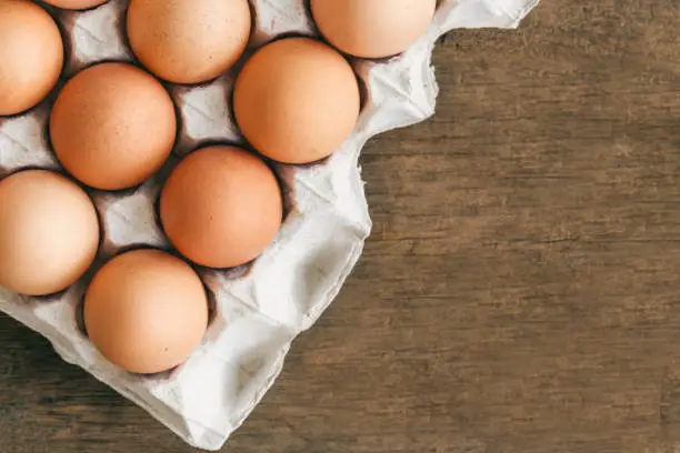 Fresh eggs in egg rack put on wood table. Prepare chicken eggs for cooking or bakery on rustic wood table. Top view or flat lay concept  of fresh eggs with copy space for background or wallpaper.