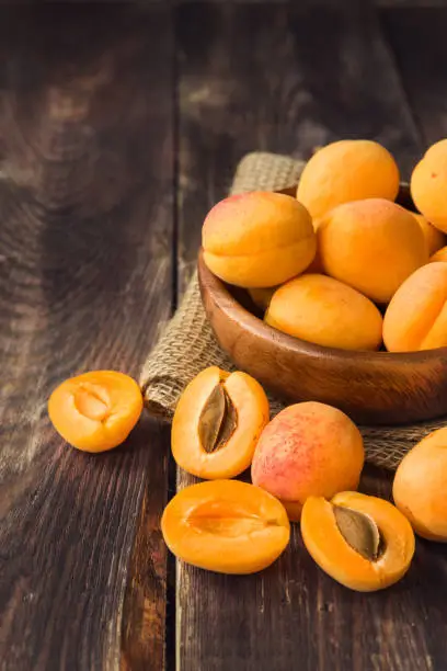 Fresh organic apricots in wooden bowl on rustic wooden background