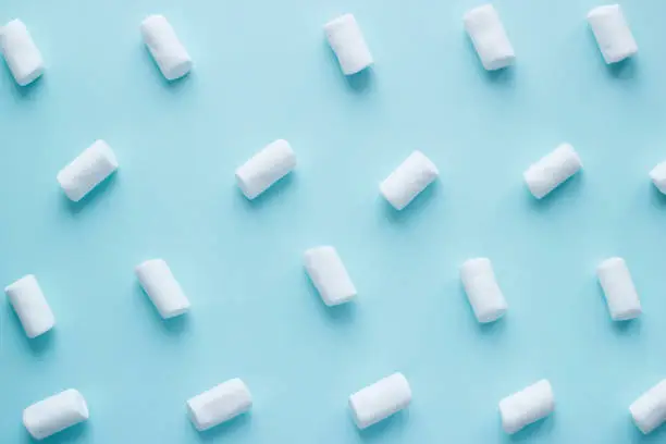 Geometric pattern of white marshmallows on blue pastel background. Food concept in minimal flatlay style. Horizontal image top view.