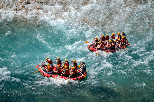 The high-flowing wavy stream is flowing fiercely. Shot from above. Red boat.Turquoise white color stream.Canyon area.Mediterranean.People in the boat have helmets and life jackets.The boat is about to crash into each other.Beşkonak/Antalya-Turkey,05/21/2022