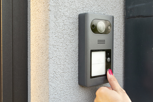 Woman's hand pressing a button on an intercom