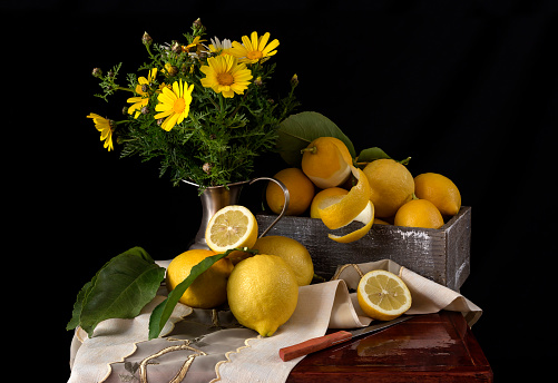Still life with yellow daisies and a lemon on a table close-up