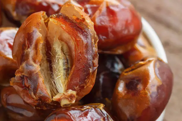 Khalas date palm on wood table in close up with copy space for background or wallpaper. Dates fruit is food for Ramadan or medjool. Delicious dried fruit with sweet taste and have high fiber.