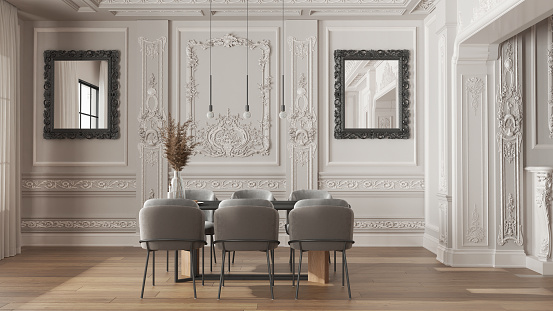 Modern furniture in classic apartment in white tones, minimalist dining room with table and armchairs, sofa, pendant lamps. Plaster molded walls and parquet. Vintage interior design