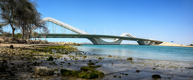 Panoramic view at Sheikh Zayed Bridge connecting Abu Dhabi island to the rest of the emirate low angle view by the sea. United Arab Emirates capital city entrance