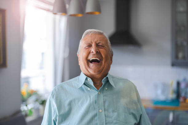 Happy senior man laughing in his home stock photo