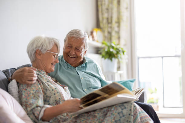 istock Elderly couple looking at a photo album while sitting on a sofa 1402178616